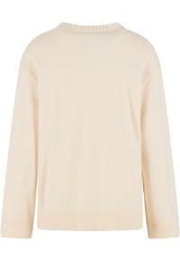 Krém színű kötött pulóver laza szabással, bordás nyakkivágással és mandzsettával, valamint oldalsó hasítékokkal az alján. Puha textúrájú és könnyű anyagból készült.