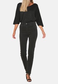 Svart glittrig topp kombinerad med hög midja svarta jeans; slätt tyg, slim fit och subtila detaljer; bärs med svarta remsandaler.