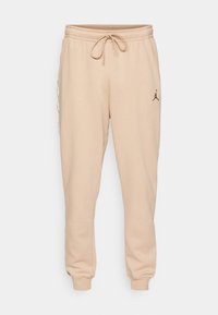 Beige sweatpants med elastisk midja och dragsko. Har en liten svart logotyp på låret och kontrasterande sidopaneldesign.