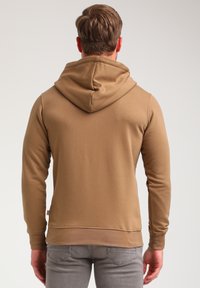 Bruine hoodie met een kangoeroezak, verstelbare capuchon met trekkoord, aansluitende mouwen en geribbelde manchetten. Glad textuur, casual ontwerp.