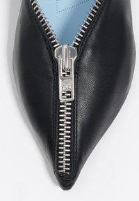 Czarny skórzany but z wąskim noskiem, z srebrnym suwakiem z przodu. Wnętrze w jasnoniebieskim kolorze.