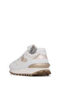 Scarpe da ginnastica bianche con un accento in oro metallico, dotate di una tomaia in tessuto testurizzato, lacci piatti e una suola spessa con un motivo ondulato.