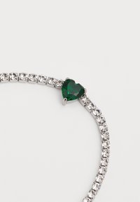 Bracciale argento con un gemma verde a forma di cuore, circondata da rhinestone trasparenti, che mostra una finitura liscia e lucida.