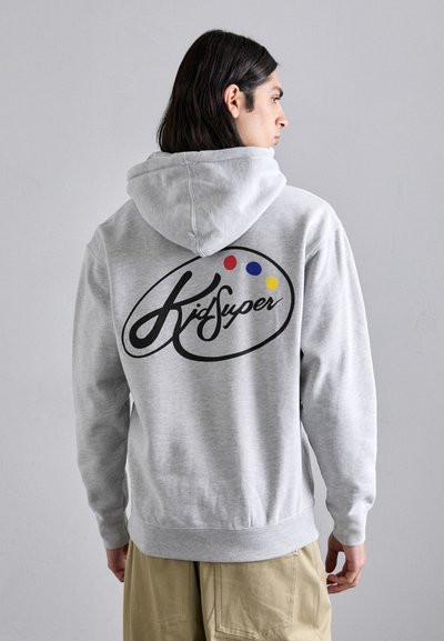 Gray hoodie featuring a large black "KidSuper" logo and colorful dots on the back. Constructed from soft fabric with a relaxed fit.