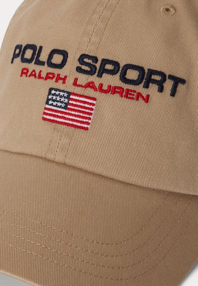 Καφέ καπέλο του μπέιζμπολ με κεντημένα τα γράμματα "POLO SPORT" και "RALPH LAUREN" σε ναυτικό μπλε. Διαθέτει ένα μικρό έμπλαστρο με την αμερικανική σημαία. Κατασκευασμένο από καμβά.