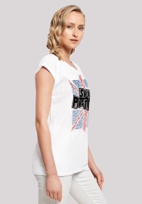 White short-sleeve t-shirt featuring a Union Jack design with blue and red text reading "Sex Positive," made from soft cotton material.