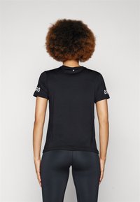 T-shirt atlético preto de mangas curtas com decote arredondado, textura suave, apresentando detalhes de logótipo em branco nas mangas.