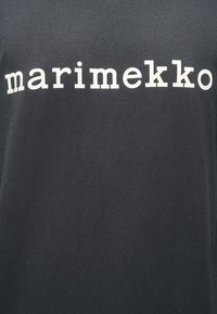Μαύρο βαμβακερό μπλουζάκι με λευκά γράμματα σε μπλοκ που σχηματίζουν τη λέξη «marimekko» στο στήθος. Μαλακή υφή με απλό σχέδιο.