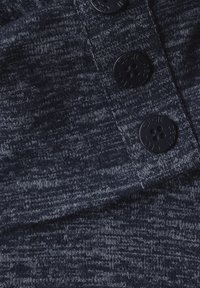 Tessuto a maglia navy con un motivo testurizzato e bottoni neri come dettagli. Il materiale appare morbido e leggermente elasticizzato.