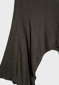 Tmavosivá pletená látka s jemným, štruktúrovaným vzorom, voľne previazaná v plynulých záhyboch na svetlom pozadí.