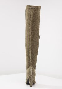 Stivali alti fino al ginocchio, di colore verde oliva con una finitura strutturata e lucente. Tacco affilato e zip sul retro per un'ottima vestibilità, progettati con una silhouette elegante.