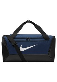 Sac de sport en nylon bleu marine avec des accents noirs, arborant un grand logo Nike blanc, des doubles zips et une bandoulière réglable noire.