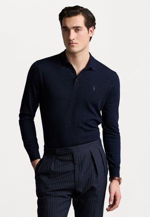 Marineblauwe polo met lange mouwen, voorzien van een kraag en een klein geborduurd logo. Gepaard met gestreepte broek in een gestructureerde pasvorm.