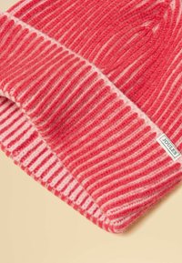 Rdeča in svetlo rožnata črtasta pletena volna kapa z zavihkom in majhno etiketo blagovne znamke Joules na zavihku.