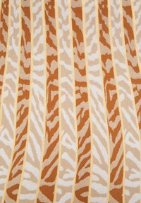 Tissu avec un motif de tigre rayé en marron, beige et blanc, accentué par des lignes jaunes, présentant une texture douce.