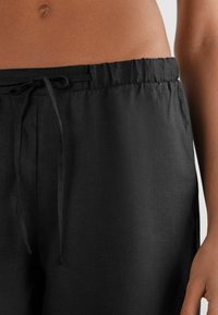 Svarta linnebyxor med dragsko i midjan och en mjuk textur; skräddarsydda för en avslappnad passform med diskret veck fram.