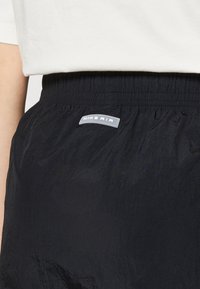 Svarta Nike Air-shorts gjorda av lätt material med ett elastiskt midjeband. Har en framträdande logobadge på framsidan.