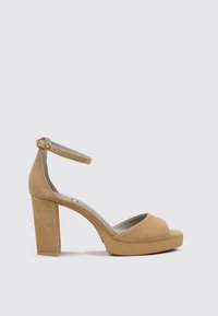 Sandalias de plataforma de ante beige con punta abierta, tira en el tobillo y un tacón alto y grueso. Superficie texturizada, diseño minimalista.