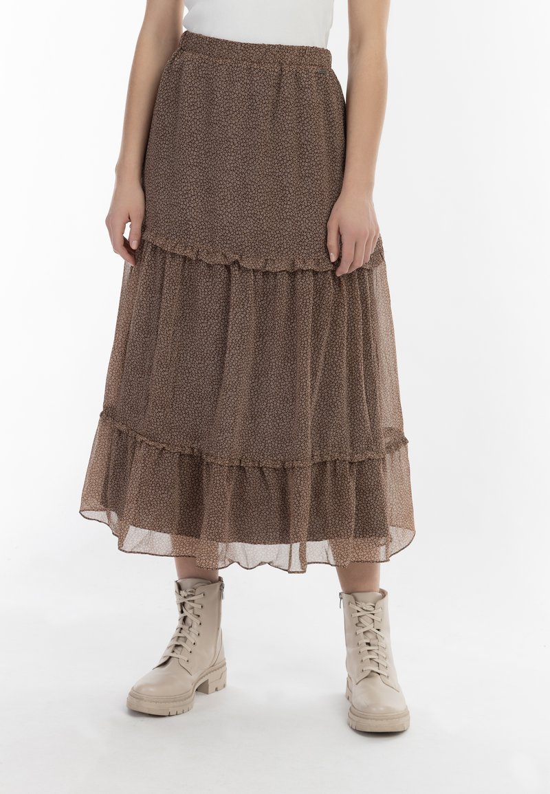 Gonna maxi marrone a strati realizzata in tessuto leggero e semi-trasparente con motivo floreale. Presenta una vita elastica e dettagli a volant sulle cuciture.