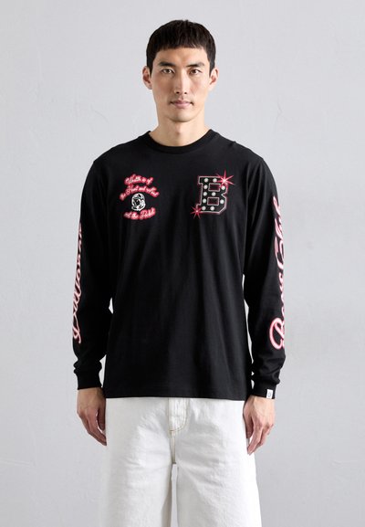 Black long-sleeve shirt featuring graphic prints in red and white, round neckline, and fitted cuffs. Notable "B" design on the chest.
