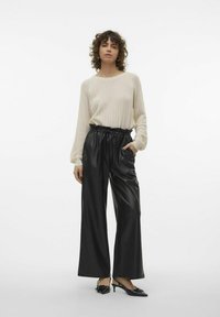 Crème geribbelde trui met lange mouwen, gecombineerd met zwarte high-waisted wijde leren broeken met een elastische tailleband.