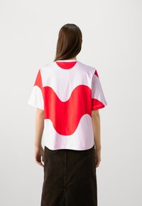 Camiseta de algodón de manga corta con un patrón de olas en rojo y blanco en la parte posterior. Corte relajado con escote redondo. Textura suave.