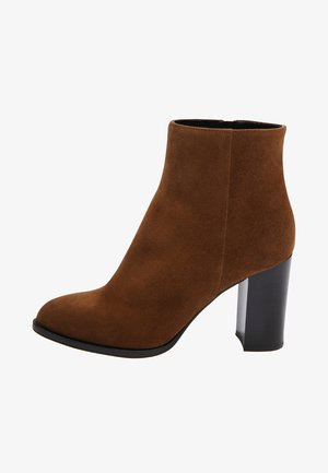 Bota de ante marrón hasta el tobillo con puntera redondeada y tacón alto negro de bloque, cierre lateral con cremallera, mostrada sobre fondo blanco.