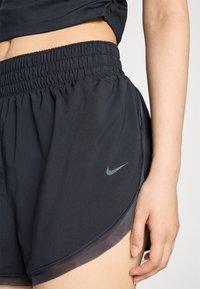 Čierne športové šortky s elastickým pásom, s nenápadným logom Nike, hladkou textúrou a ľahkým dizajnom so bočnými rozparkami.