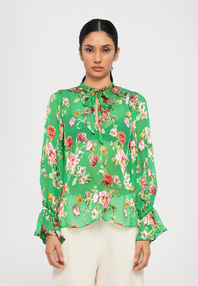 Green floral blouse with a bow tie neckline, long sleeves, and ruffled cuffs. Features a lightweight, semi-transparent fabric with multicolored flowers.