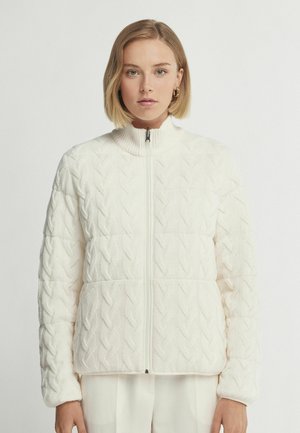 Witte gebreide jas met een hoge kraag, een textuur van kabelpatronen, een volledige ritssluiting en een iets pufferige silhouet, ontworpen voor warmte en comfort.