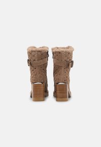 Bottines en cuir suédé marron avec doublure en fausse fourrure, design matelassé, clous en argent et un talon en bois épais. Sangle ajustable avec détail de boucle.