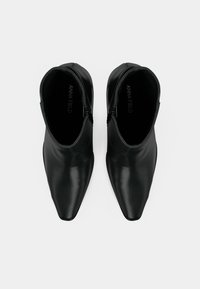 Μαύρα μποτάκια αστραγάλου από λείο δέρμα, με μυτερή μύτη, εσωτερικό φερμουάρ και διακριτικές ελαστικές πλαϊνές πινελιές για ευκαμψία.