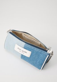 Denim zip pouch with light and dark blue sections, white logo, silver zipper, and interior card slots in a beige lining.