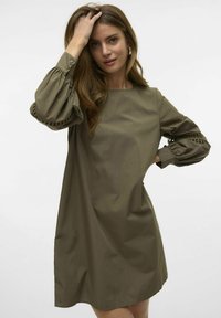 Olijfgroene jurk met korte mouwen en een ontspannen pasvorm. Gekenmerkt door knoopmanchetten met plooien en een simdetail langs de mouwen. Zachte textuur.