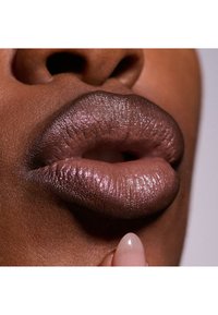Zbliżenie na usta pomalowane błyszczącą mauve szminką. Tekstura jest gładka z delikatnym połyskiem, podkreślona wyraźnymi konturami warg.