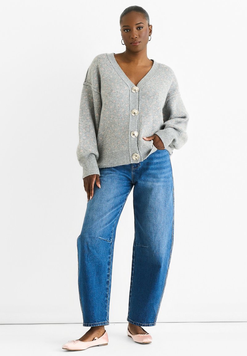 Gray knitted cardigan with a V-neck, oversized sleeves, and large buttons, paired with blue straight-leg jeans and light pink flats.