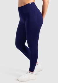 Granatowe legginsy z wysokim stanem, wykonane z elastycznego materiału, charakteryzujące się gładką teksturą i subtelnymi akcentami wzorniczymi.