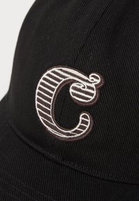 Čierny baseballový klobúk so štruktúrovaným dizajnom. Obsahuje vyšívané písmeno "C" v hnedej a bielej pruhovanej kombinácii. Textúrovaná tkanina.