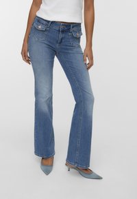 Ljusblå utsvängda jeans med fem fickor, knäppning fram och subtila blekningar. Tyget är slätt denim med en lätt sliten finish.