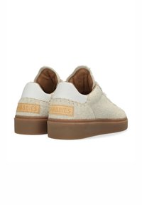 Sneakers z puszystym, jasnobeżowym wykończeniem i gładką, białą skórzaną piętą, z brązowym logo marki oraz brązową gumową podeszwą.