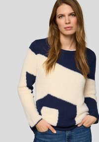 Flauschiger Strickpullover mit einem geometrischen Muster in Marineblau und Creme, Rundhalsausschnitt und langen Ärmeln. Weiche Textur mit kontrastierenden Farbblöcken.