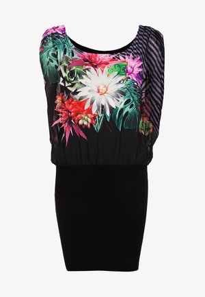 Schwarzer figurbetonter Rock mit einem lockeren, blumenmusternden Oberteil in lebhaften Farben, transparenten Ärmeln und einer taillierten Taille. Schwarze High Heels.