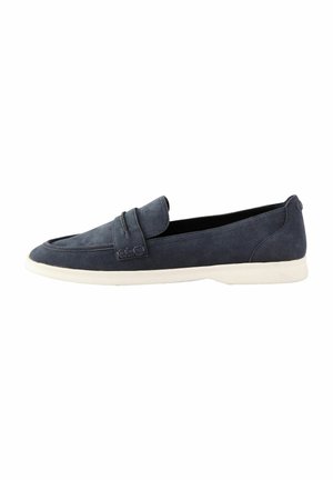 Mocassins en daim bleu marine avec une texture lisse, présentant un détail de sangle à l'avant et une semelle en caoutchouc blanche. Design glissant.