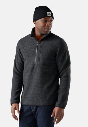 Grå fleece-pullover med halvlange lynlås, prydet med en brystlomme, ribbede mansjetter og kant. Sammen med en sort strikket beanie.