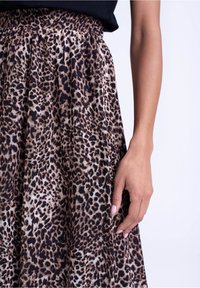Leopardprint nederdel lavet af letvægtsstof, med en tætsiddende talje og flydende plisseringer i nuancer af brunt og sort.