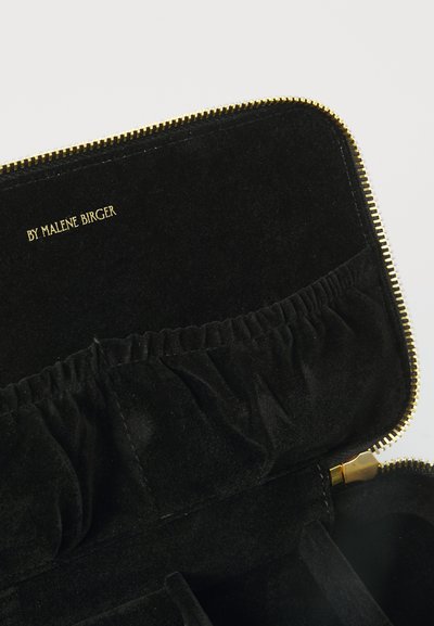Μαύρη βελούδινη τσάντα με φερμουάρ και χρυσές λεπτομέρειες, με συγκεντρωμένες θήκες και ανάγλυφο λογότυπο "BY MALENE BIRGER". Λείο υφασμάτινο τελείωμα σε όλη την επιφάνεια.