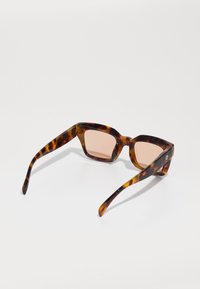 Ochelari de soare cu ramele tortoise și lentile cu nuanțe roz. Cadru geometric unghiular și tije elegante care pun în evidență un finisaj lucios.