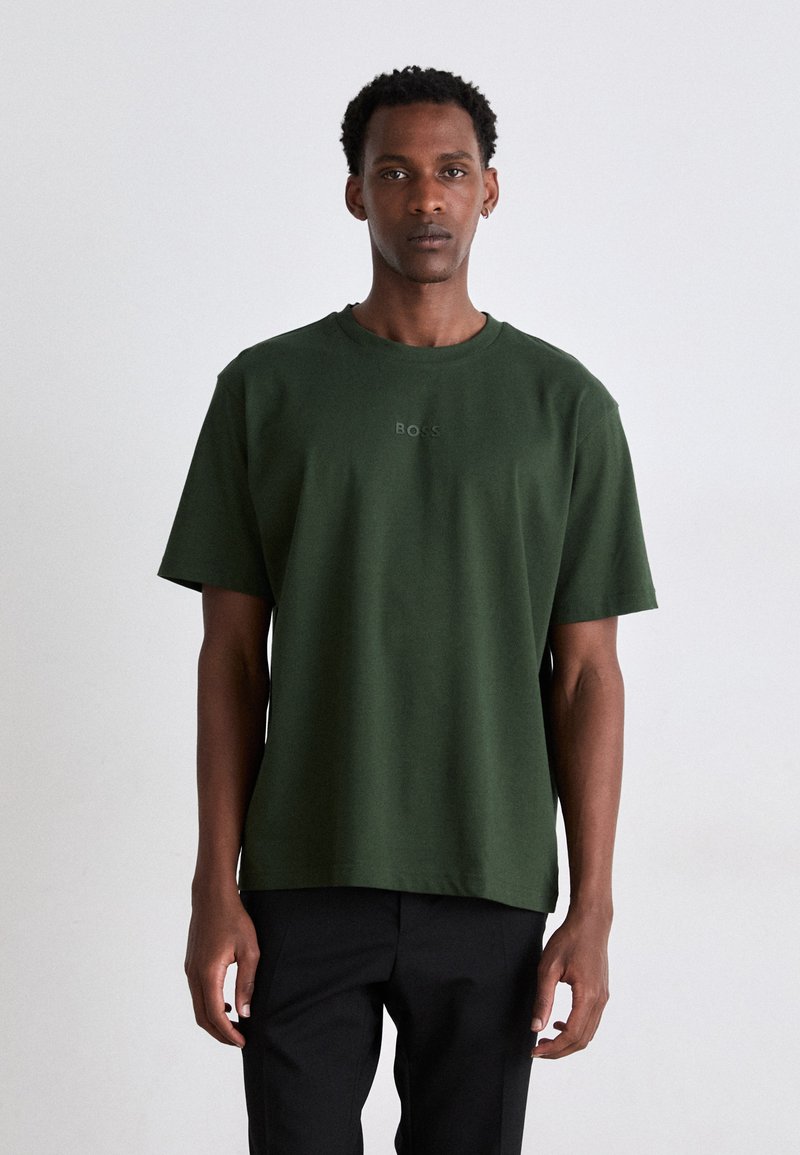 T-shirt en coton à manches courtes, de couleur vert foncé, avec un col ras du cou et un logo "BOSS" brodé subtilement à l'avant. Coupe décontractée et texture douce.