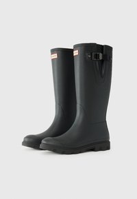 Black rubber rain boots with a smooth finish, slight heel, and lugged sole. Features a buckle accent and red logo label on the front.