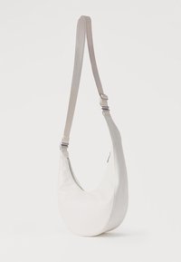Λευκή τσάντα χιαστί σε σχήμα ημισελήνου με ρυθμιζόμενο λουράκι και εμφανή φερμουάρ σε απλό φόντο.